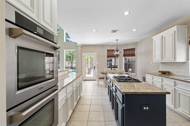 16047 Lockdale Ln, Cypress, TX 77429 - kitchen with gas stovetop, white cabinetry, decorative backsplash, light tile patterned floors, and a kitchen island