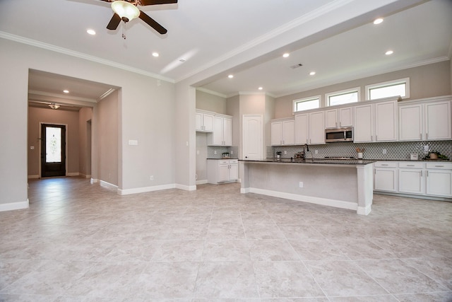 14618 Moccasin Ridge Dr, Cypress, TX 77433 - kitchen featuring stainless steel microwave, dark countertops, decorative backsplash, ceiling fan, and ornamental molding