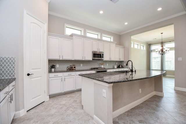 14618 Moccasin Ridge Dr, Cypress, TX 77433 - kitchen with stainless steel microwave, backsplash, dark stone counters, ornamental molding, and a kitchen island with sink