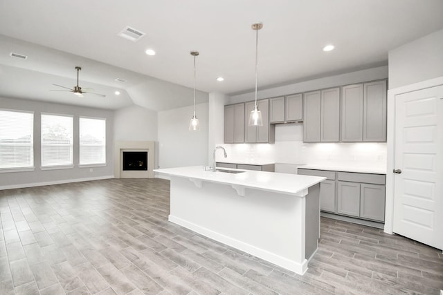 11106 Crocus Dr, Houston, TX 77044 - kitchen featuring gray cabinetry, ceiling fan, light wood-style floors, a kitchen island with sink, and tasteful backsplash