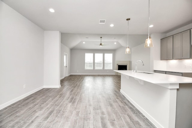 11106 Crocus Dr, Houston, TX 77044 - kitchen featuring gray cabinets, ceiling fan, a fireplace with raised hearth, light wood-type flooring, and light countertops