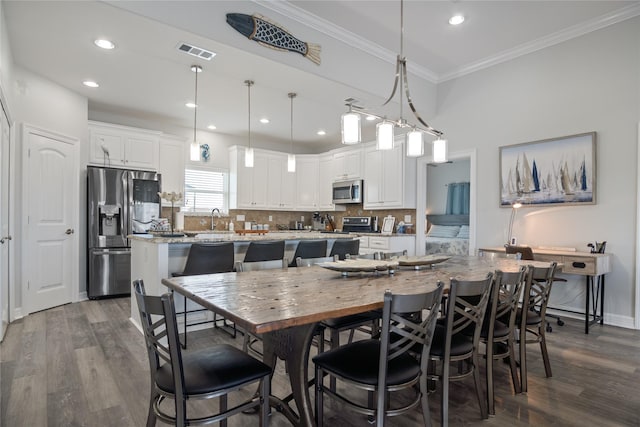 956 Biscayne, Crystal Beach, TX 77650 - kitchen with appliances with stainless steel finishes, a kitchen island, dark wood-type flooring, tasteful backsplash, and crown molding