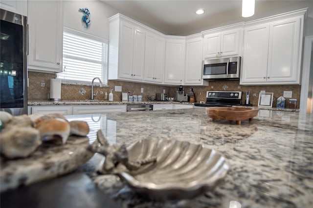 956 Biscayne, Crystal Beach, TX 77650 - kitchen featuring stainless steel microwave, range with electric cooktop, white cabinets, decorative backsplash, and light stone countertops