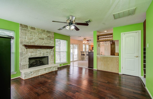 15731 Oak Mountain Dr, Houston, TX 77095 - unfurnished living room with a ceiling fan, hardwood / wood-style flooring, a stone fireplace, and a textured ceiling