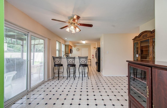 15731 Oak Mountain Dr, Houston, TX 77095 - kitchen featuring a breakfast bar, light flooring, ceiling fan, freestanding refrigerator, and a peninsula