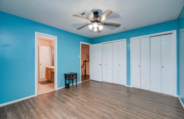 15731 Oak Mountain Dr, Houston, TX 77095 - unfurnished bedroom featuring multiple closets, wood finished floors, connected bathroom, and a ceiling fan
