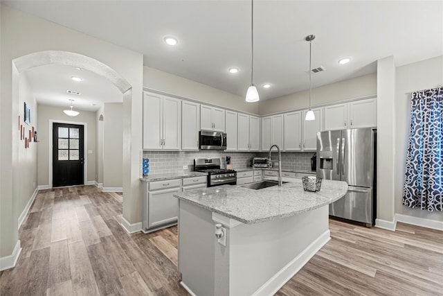 2922 Muhley St, Katy, TX 77493 - kitchen with stainless steel appliances, arched walkways, light wood-type flooring, tasteful backsplash, and recessed lighting