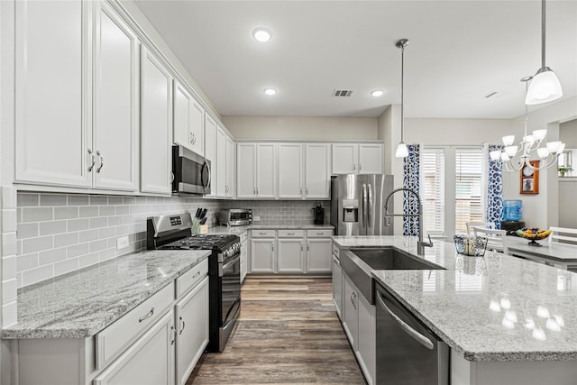 2922 Muhley St, Katy, TX 77493 - kitchen featuring appliances with stainless steel finishes, a kitchen island with sink, white cabinetry, a chandelier, and backsplash