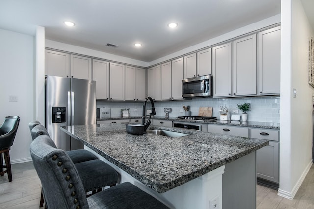 8023 Royal Palm Dr, Fulshear, TX 77441 - kitchen featuring stainless steel appliances, gray cabinets, a breakfast bar area, dark stone countertops, and recessed lighting
