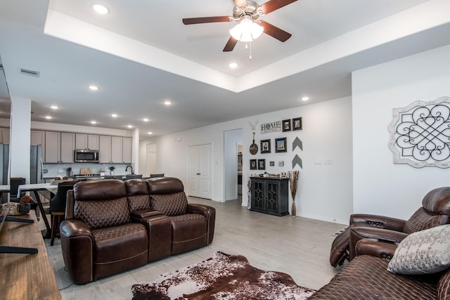 8023 Royal Palm Dr, Fulshear, TX 77441 - living room featuring a ceiling fan, recessed lighting, light wood-style flooring, and a tray ceiling