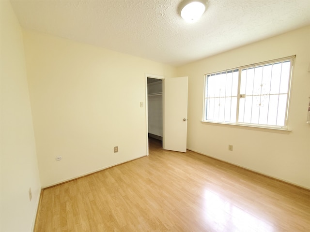 9206 Beringwood Dr, Houston, TX 77083 - unfurnished bedroom featuring light wood finished floors, a textured ceiling, a walk in closet, and a closet