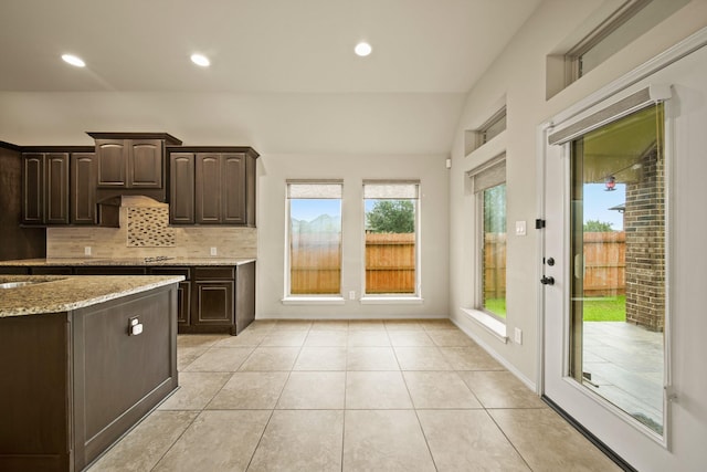 1303 Paradise Creek Ln, Rosenberg, TX 77471 - kitchen featuring backsplash, dark brown cabinets, light stone counters, light tile patterned floors, and recessed lighting