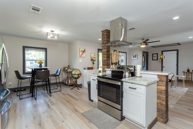510 Jerry St, Houston, TX 77022 - kitchen with stainless steel appliances, island exhaust hood, light wood-style flooring, white cabinets, and ceiling fan