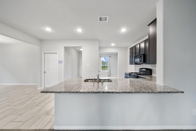 11103 Larkspur Dale Ct, Houston, TX 77044 - kitchen featuring black appliances, dark stone counters, a peninsula, recessed lighting, and decorative backsplash