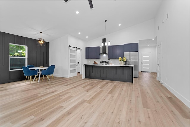 4021 King St, Houston, TX 77026 - kitchen featuring stainless steel fridge with ice dispenser, a barn door, wall chimney range hood, light countertops, and light wood-type flooring