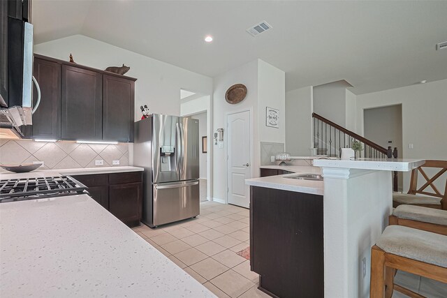 406 Riesling Dr, Alvin, TX 77511 - kitchen featuring appliances with stainless steel finishes, a breakfast bar area, tasteful backsplash, dark brown cabinetry, and a peninsula