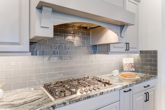 28723 Eden Creek Trl, Fulshear, TX 77441 - kitchen with stainless steel gas stovetop, backsplash, white cabinetry, and light stone counters