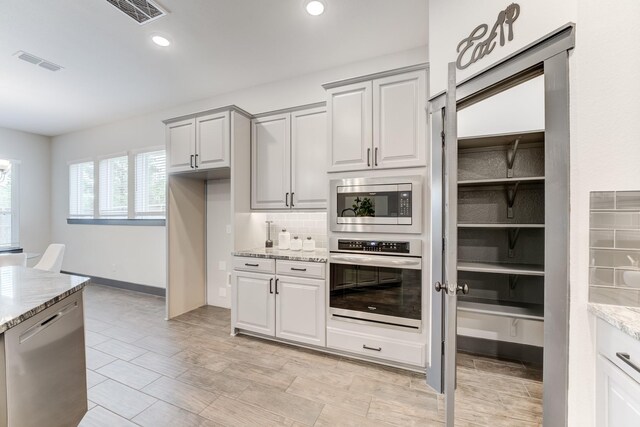 28723 Eden Creek Trl, Fulshear, TX 77441 - kitchen featuring stainless steel appliances, light stone countertops, decorative backsplash, recessed lighting, and light wood-type flooring