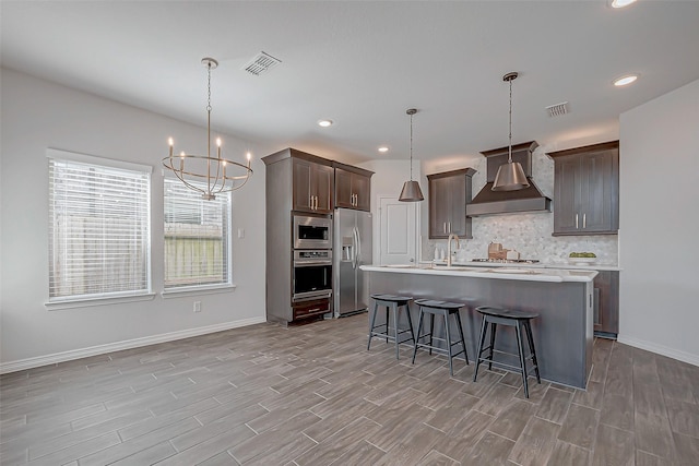 8934 Stanley Oak Dr, Missouri City, TX 77459 - kitchen featuring custom exhaust hood, stainless steel appliances, tasteful backsplash, light countertops, and a breakfast bar