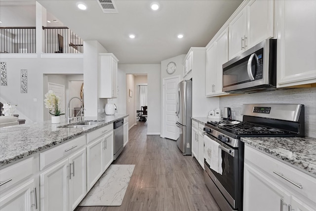 3823 Fleetwood Falls Ln, Spring, TX 77386 - kitchen with appliances with stainless steel finishes, white cabinetry, decorative backsplash, light wood-style flooring, and recessed lighting