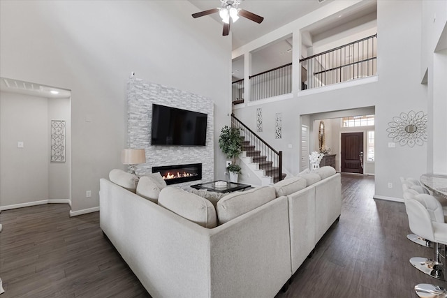 3823 Fleetwood Falls Ln, Spring, TX 77386 - living room featuring a high ceiling, dark wood finished floors, a fireplace, a ceiling fan, and stairs