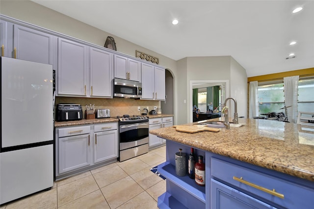 66 N Rocky Point Cir, Spring, TX 77389 - kitchen featuring appliances with stainless steel finishes, tasteful backsplash, light tile patterned floors, recessed lighting, and light stone counters