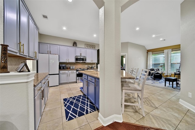 66 N Rocky Point Cir, Spring, TX 77389 - kitchen with appliances with stainless steel finishes, decorative backsplash, arched walkways, light stone countertops, and recessed lighting