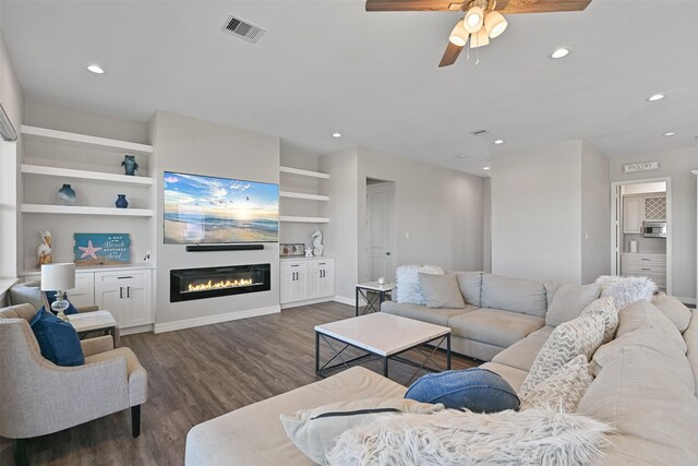 3914 Curlew Dr, Galveston, TX 77554 - living room with dark wood finished floors, recessed lighting, a ceiling fan, a glass covered fireplace, and built in shelves
