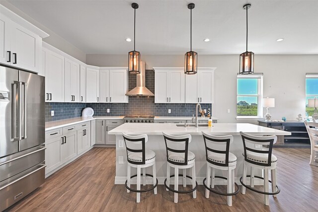 3914 Curlew Dr, Galveston, TX 77554 - kitchen with high end refrigerator, light countertops, wood finished floors, a kitchen island with sink, and backsplash
