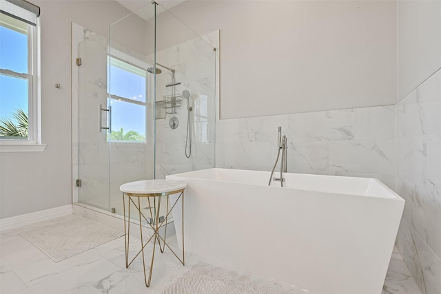 3914 Curlew Dr, Galveston, TX 77554 - bathroom with marble tiled floors, tile walls, plenty of natural light, and a soaking tub