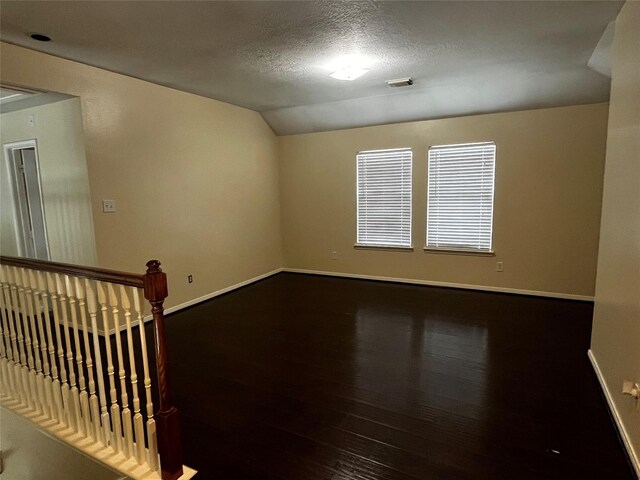6830 Silver Shores Ln, Katy, TX 77449 - empty room featuring vaulted ceiling, wood finished floors, and a textured ceiling