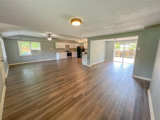 507 Elk Dr, Crosby, TX 77532 - unfurnished living room featuring a textured ceiling, dark wood-type flooring, cooling unit, healthy amount of natural light, and a ceiling fan