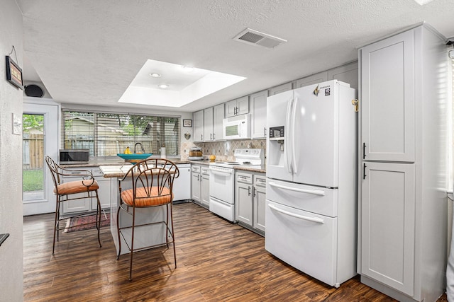 5427 Cairnleigh Dr, Houston, TX 77084 - kitchen with white appliances, dark wood finished floors, a skylight, a kitchen breakfast bar, and a textured ceiling