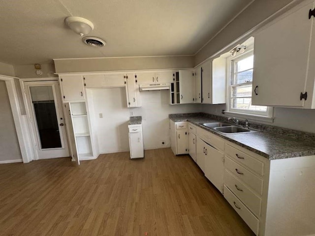 402 51st St, Lubbock, TX 79404 - kitchen featuring white cabinetry, wood finished floors, dark countertops, and under cabinet range hood