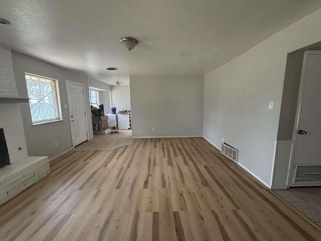 5431 45th St, Lubbock, TX 79414 - unfurnished living room with light wood-style flooring and a textured ceiling