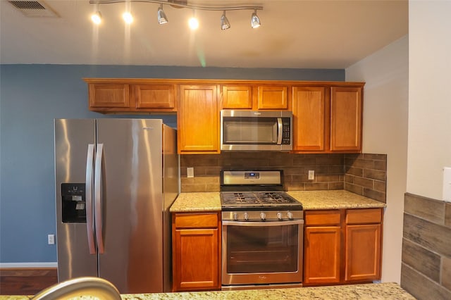 1515 Saulnier St, Houston, TX 77019 - kitchen with stainless steel appliances, light stone counters, decorative backsplash, and brown cabinets