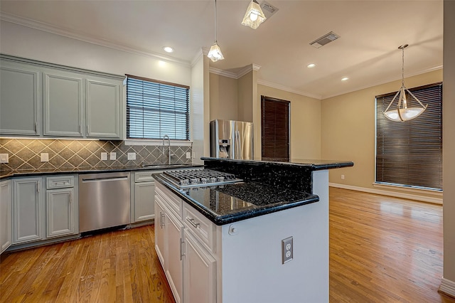 5331 Nolda St Unit A, Houston, TX 77007 - kitchen with appliances with stainless steel finishes, light wood-style flooring, a kitchen island, tasteful backsplash, and ornamental molding