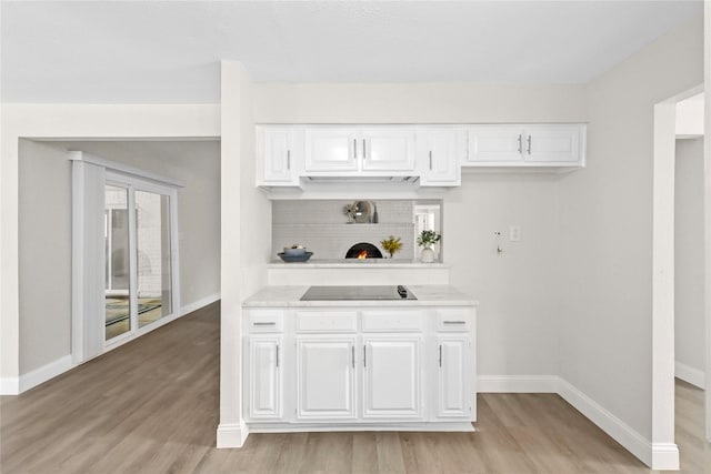 3101 Possum Trot St, Brenham, TX 77833 - kitchen featuring black electric stovetop, light countertops, light wood finished floors, and white cabinets