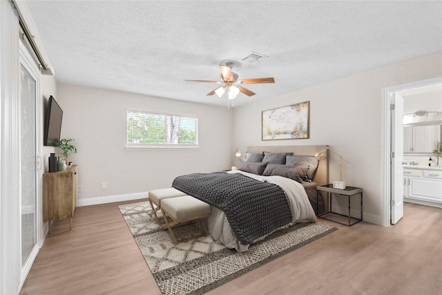 3101 Possum Trot St, Brenham, TX 77833 - bedroom with light wood-style flooring, a textured ceiling, a ceiling fan, and connected bathroom