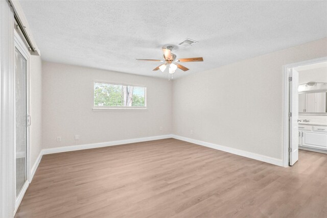 3101 Possum Trot St, Brenham, TX 77833 - unfurnished bedroom featuring light wood-style floors, a textured ceiling, a ceiling fan, and ensuite bath
