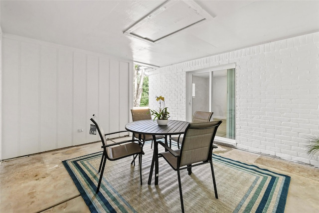 3101 Possum Trot St, Brenham, TX 77833 - dining area featuring unfinished concrete floors, brick wall, and attic access