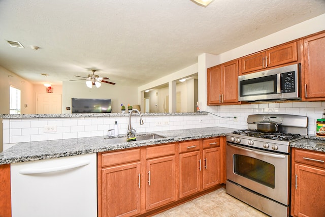 2727 Piney Lake Ct, Houston, TX 77038 - kitchen featuring appliances with stainless steel finishes, decorative backsplash, a ceiling fan, stone countertops, and brown cabinetry