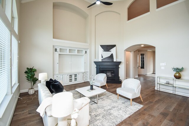 19019 Kimber Creek Ln, Cypress, TX 77429 - living area featuring a towering ceiling, arched walkways, ceiling fan, a glass covered fireplace, and wood finished floors
