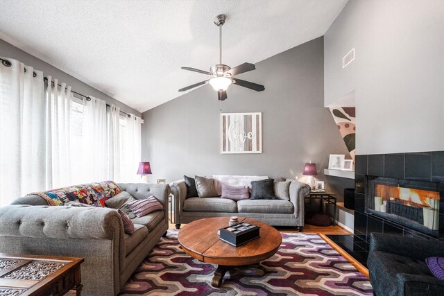 1501 Wimbledon Dr, Huntsville, TX 77340 - living area featuring vaulted ceiling, a tile fireplace, a ceiling fan, and a textured ceiling