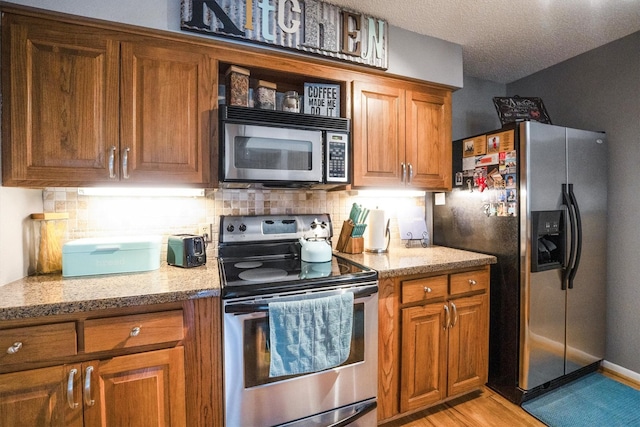 1501 Wimbledon Dr, Huntsville, TX 77340 - kitchen with appliances with stainless steel finishes, brown cabinetry, tasteful backsplash, and a textured ceiling