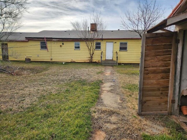 701 E Purdue St, Lubbock, TX 79403 - back of property with entry steps, a yard, and a chimney