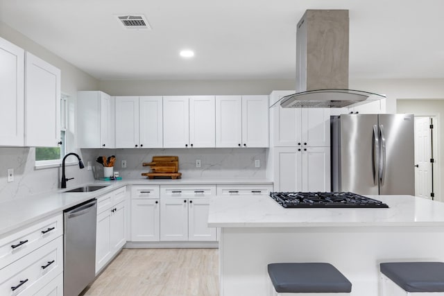 3915 Southmore Cir, Houston, TX 77004 - kitchen featuring stainless steel appliances, island exhaust hood, white cabinetry, a kitchen breakfast bar, and recessed lighting