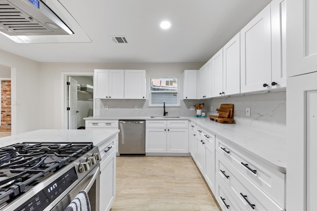 3915 Southmore Cir, Houston, TX 77004 - kitchen featuring appliances with stainless steel finishes, white cabinetry, light stone countertops, and recessed lighting