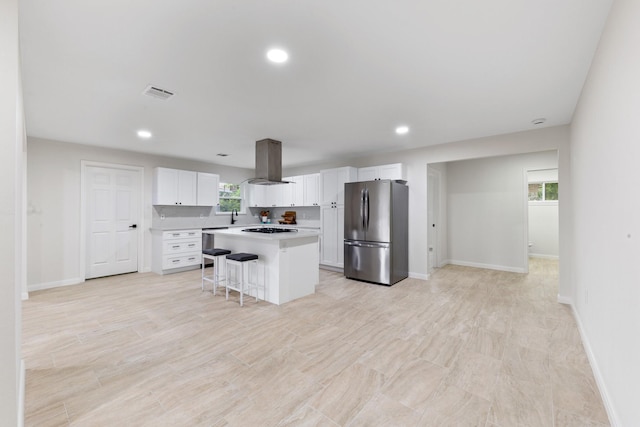 3915 Southmore Cir, Houston, TX 77004 - kitchen with freestanding refrigerator, white cabinetry, island range hood, a kitchen island, and a kitchen breakfast bar