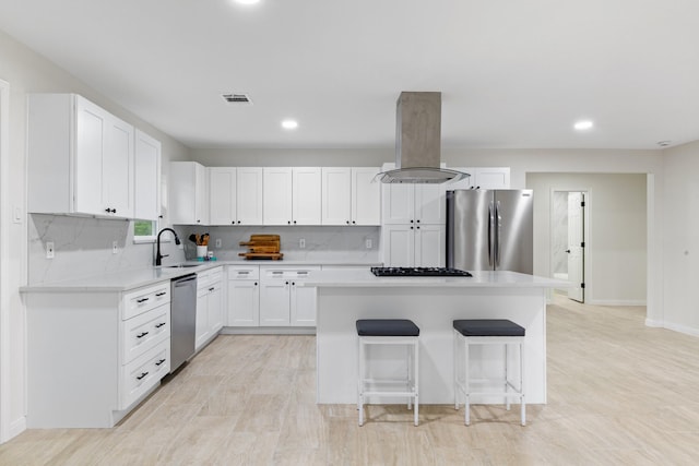 3915 Southmore Cir, Houston, TX 77004 - kitchen featuring appliances with stainless steel finishes, island range hood, a center island, light countertops, and a breakfast bar